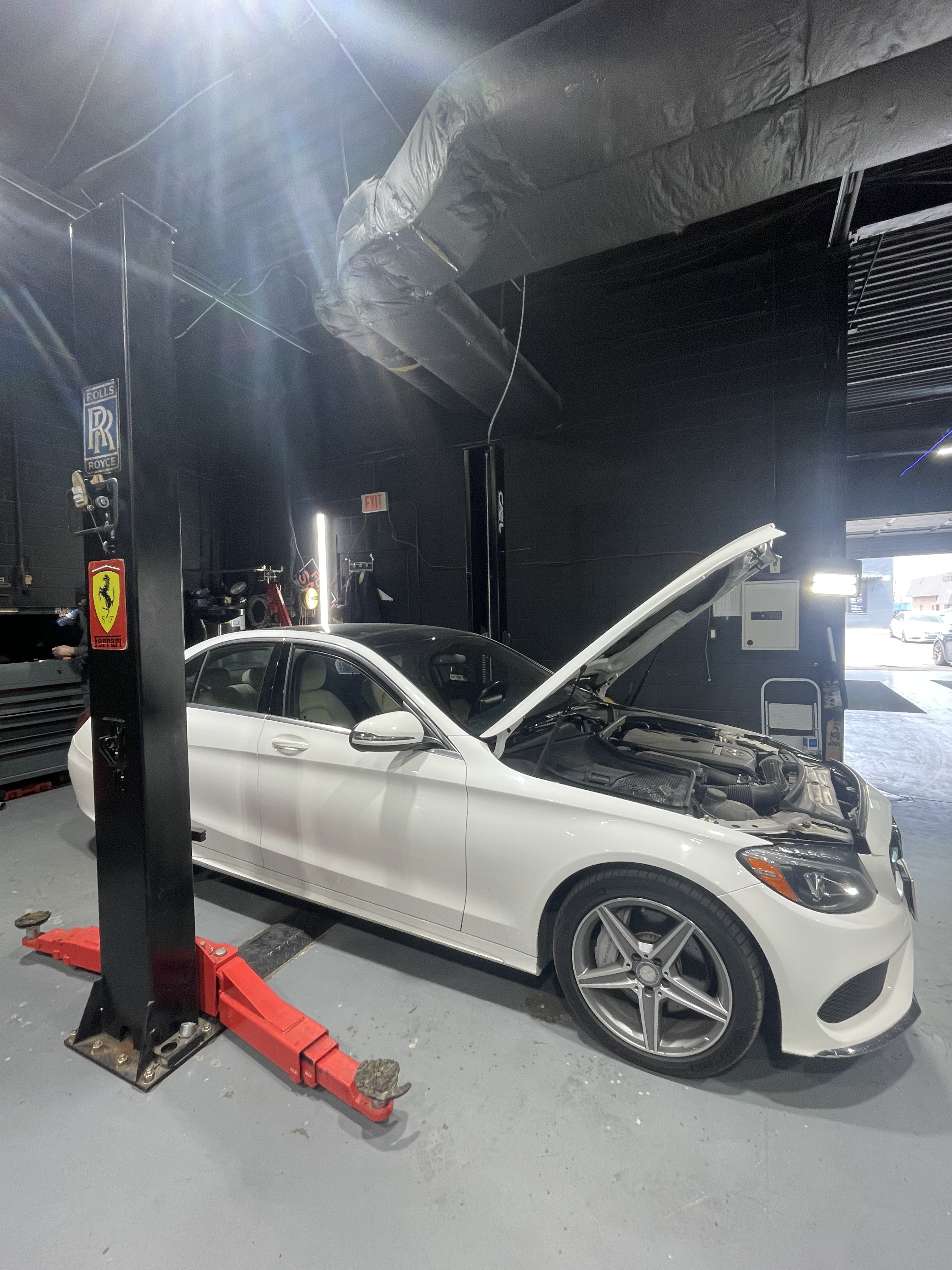 White Mercedes C-Class on lift, engine bay open